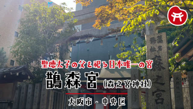 鵲森宮の石の鳥居としめ縄、右手に「森之宮」と刻まれた社号標、奥に朱色の社殿と背後のビル
